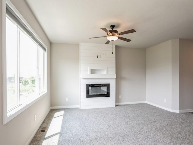 unfurnished living room with carpet flooring, a large fireplace, and ceiling fan