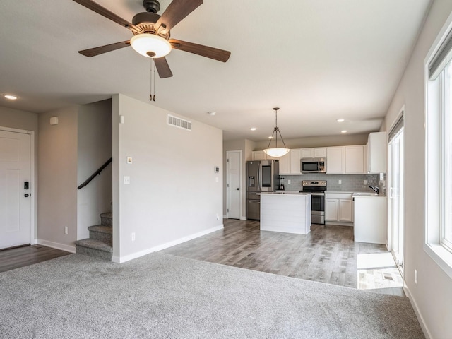 kitchen featuring white cabinetry, a kitchen island, pendant lighting, stainless steel appliances, and backsplash