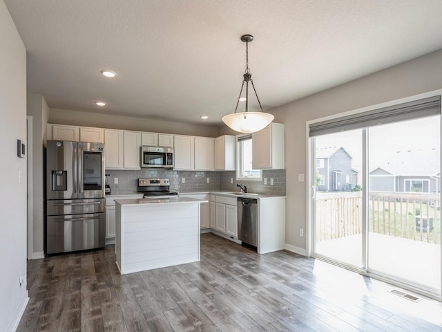 kitchen featuring pendant lighting, sink, appliances with stainless steel finishes, white cabinetry, and decorative backsplash