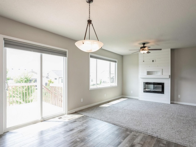 unfurnished living room featuring hardwood / wood-style floors, a textured ceiling, a large fireplace, and ceiling fan