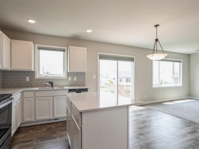 kitchen featuring stainless steel electric stove, a kitchen island, sink, white cabinets, and hanging light fixtures