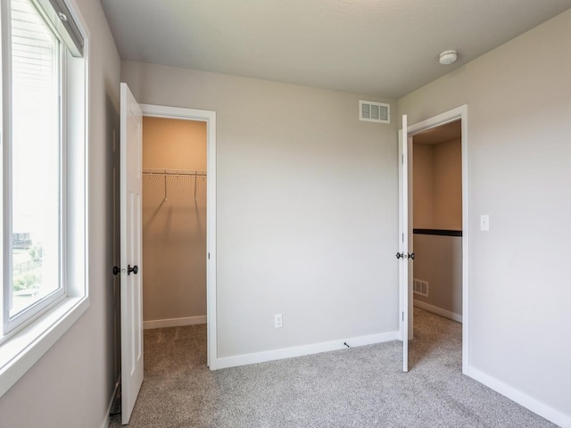 unfurnished bedroom featuring light colored carpet, a spacious closet, and a closet