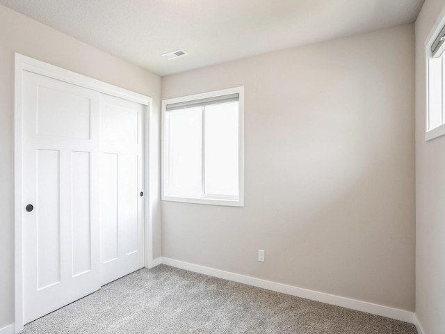 unfurnished bedroom with light colored carpet and a closet