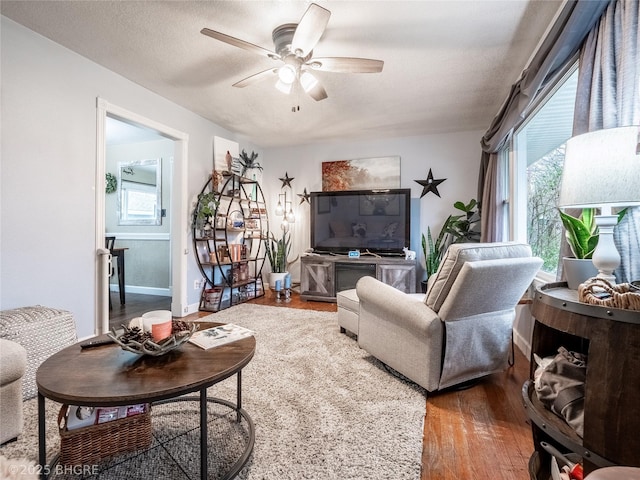 living room with ceiling fan, a textured ceiling, wood-type flooring, and a healthy amount of sunlight