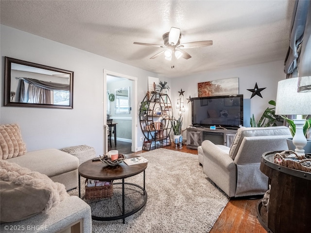 living room with a textured ceiling, wood-type flooring, and ceiling fan