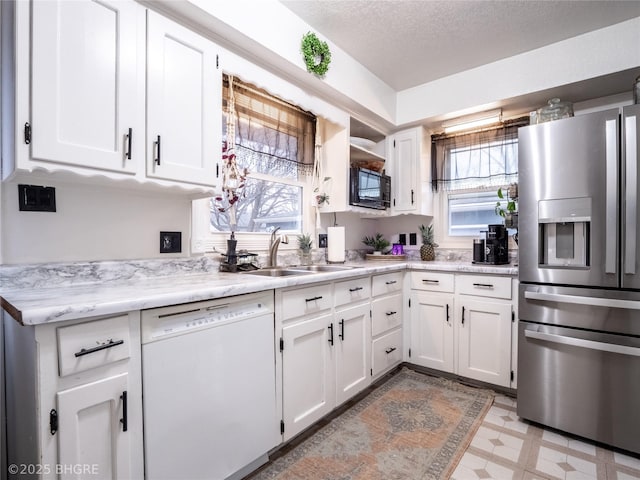 kitchen with sink, stainless steel refrigerator with ice dispenser, white dishwasher, a textured ceiling, and white cabinets