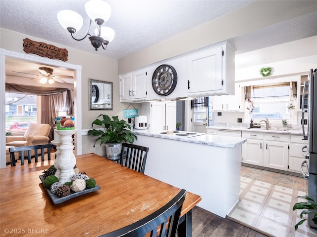 kitchen with a textured ceiling, light stone countertops, kitchen peninsula, and white cabinets