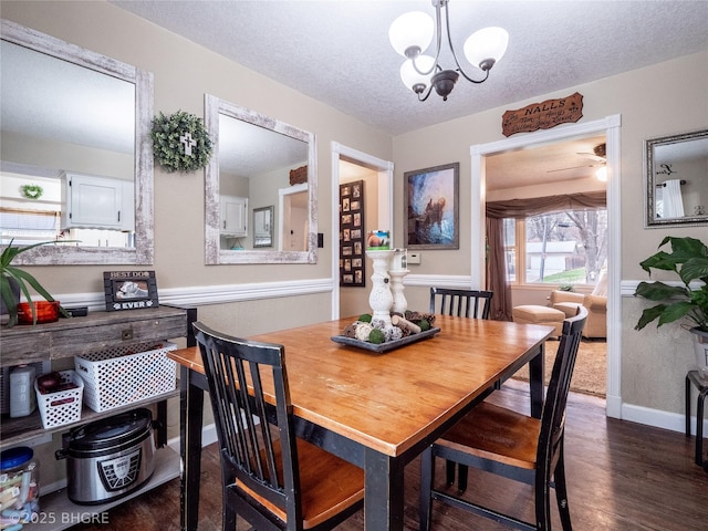 dining space with dark hardwood / wood-style flooring, ceiling fan with notable chandelier, and a textured ceiling