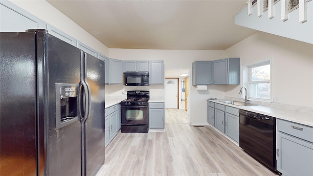 kitchen featuring gray cabinetry, sink, light hardwood / wood-style flooring, and black appliances