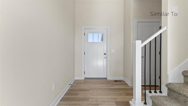 foyer featuring light wood finished floors, stairs, and baseboards