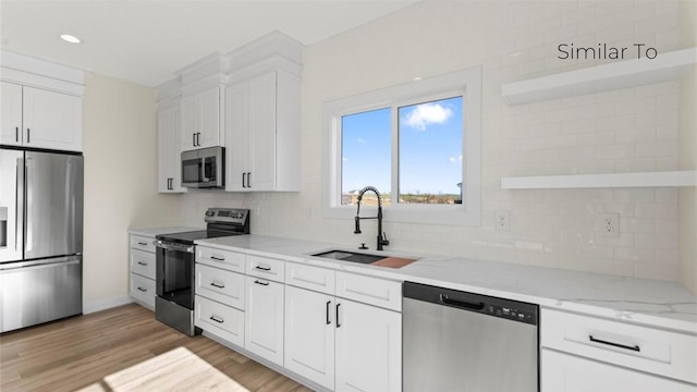 kitchen with stainless steel appliances, a sink, white cabinetry, open shelves, and tasteful backsplash