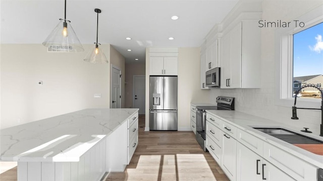 kitchen with stainless steel appliances, light wood-type flooring, white cabinetry, pendant lighting, and a sink