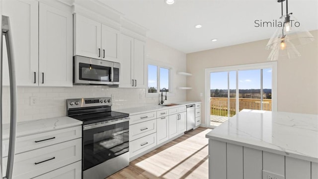 kitchen with decorative backsplash, appliances with stainless steel finishes, white cabinetry, open shelves, and a sink