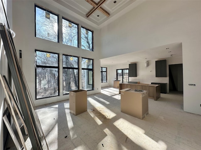 living area with coffered ceiling and a high ceiling