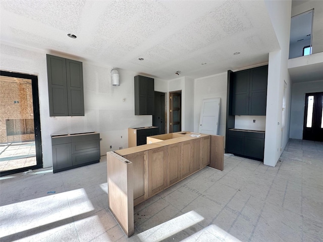 kitchen featuring a textured ceiling, light floors, and a center island