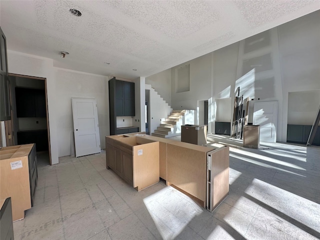 kitchen featuring a textured ceiling, a kitchen island, and a high ceiling