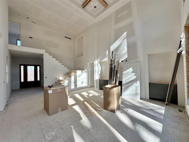 entryway with stairway, visible vents, and a towering ceiling