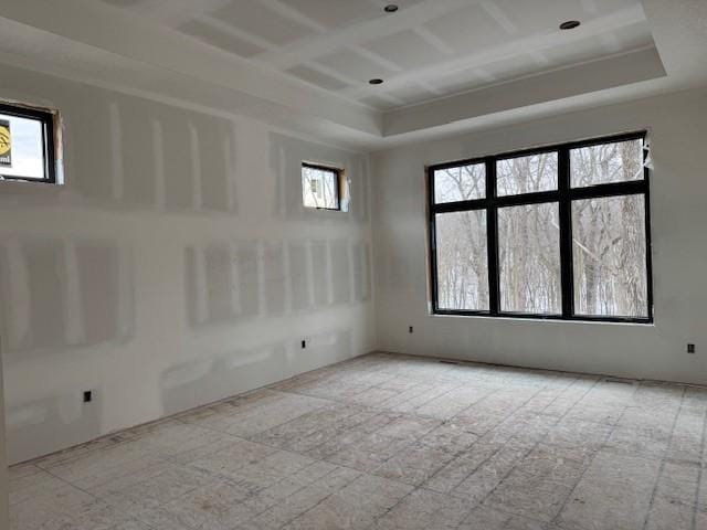 empty room with a raised ceiling and coffered ceiling