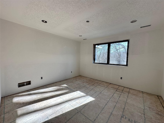 unfurnished room with visible vents and a textured ceiling