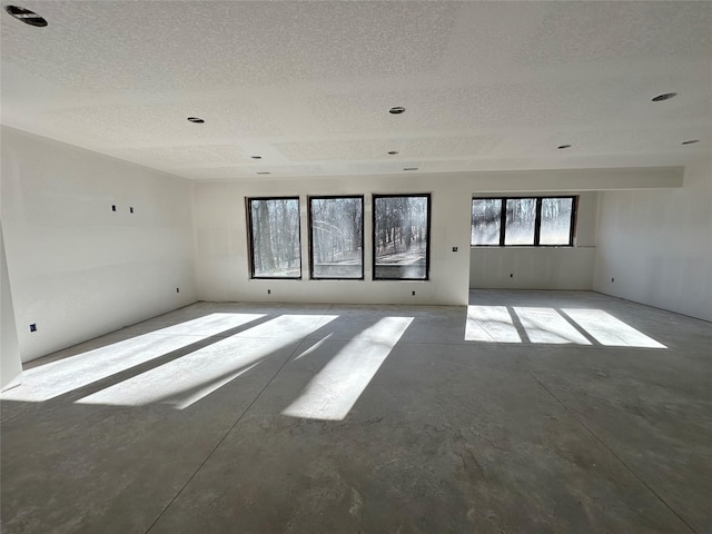 spare room with unfinished concrete floors and a textured ceiling