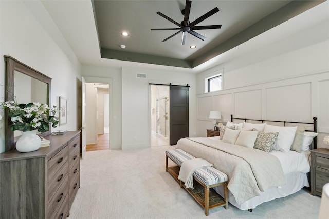 10430 Thorne Dr, West Des Moines, IA 50266 - bedroom with a barn door, recessed lighting, light colored carpet, a tray ceiling, and a decorative wall