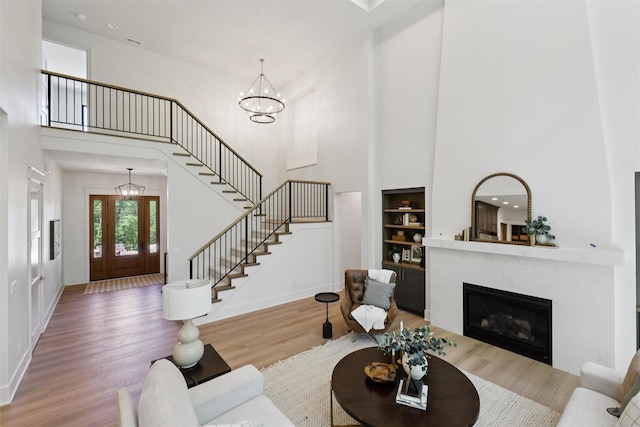 10430 Thorne Dr, West Des Moines, IA 50266 - living room featuring a towering ceiling, a chandelier, stairway, built in shelves, and wood finished floors