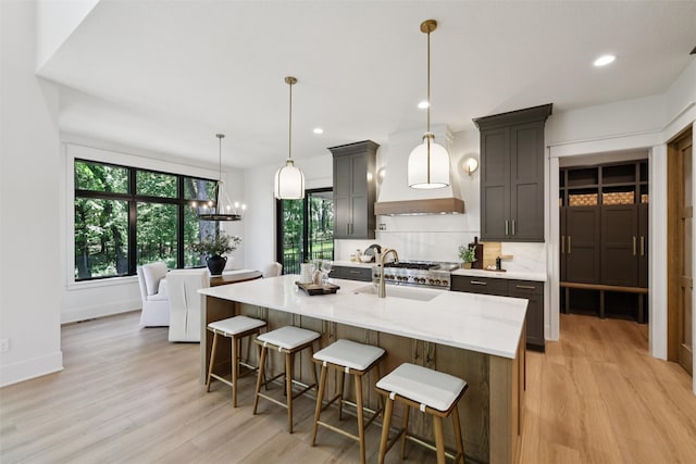 10430 Thorne Dr, West Des Moines, IA 50266 - kitchen featuring light wood-type flooring, healthy amount of natural light, a center island with sink, light stone countertops, and recessed lighting