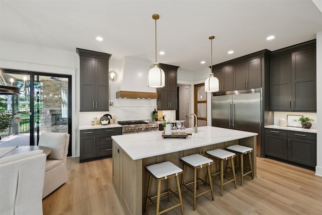 10430 Thorne Dr, West Des Moines, IA 50266 - kitchen featuring light wood-style floors, high end appliances, custom range hood, a breakfast bar, and recessed lighting