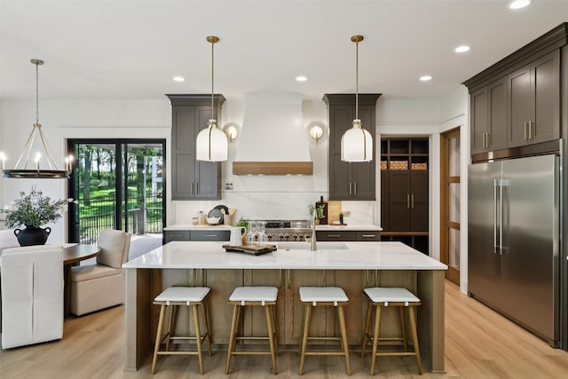 10430 Thorne Dr, West Des Moines, IA 50266 - kitchen featuring built in fridge, custom exhaust hood, light wood-type flooring, recessed lighting, and a kitchen breakfast bar