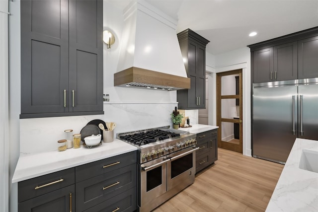 10430 Thorne Dr, West Des Moines, IA 50266 - kitchen with premium appliances, custom exhaust hood, decorative backsplash, light stone counters, and light wood-type flooring