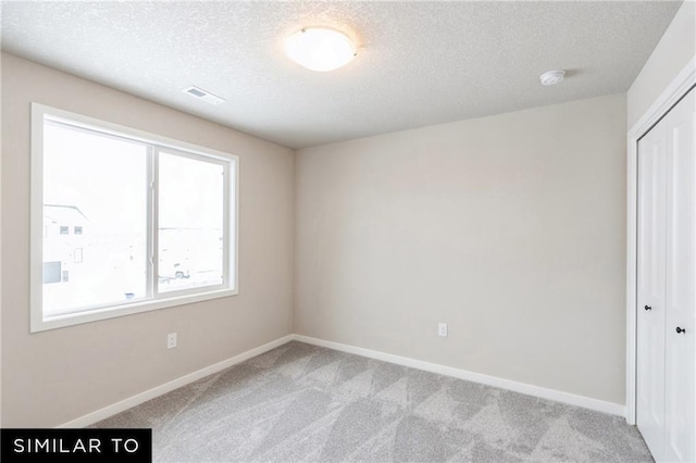 empty room featuring light colored carpet and a textured ceiling