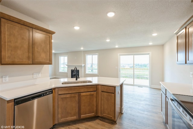 kitchen featuring a peninsula, light countertops, a sink, light wood finished floors, and stainless steel appliances