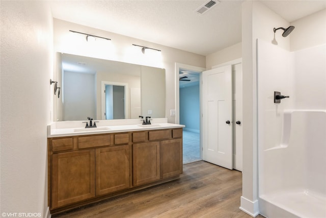 bathroom featuring a stall shower, visible vents, a sink, and wood finished floors