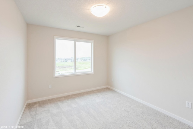 empty room with baseboards, visible vents, and light carpet