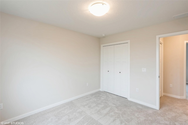 unfurnished bedroom with a closet, carpet flooring, baseboards, and visible vents