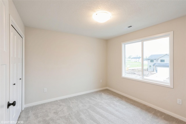 unfurnished bedroom with baseboards, light carpet, a closet, and visible vents