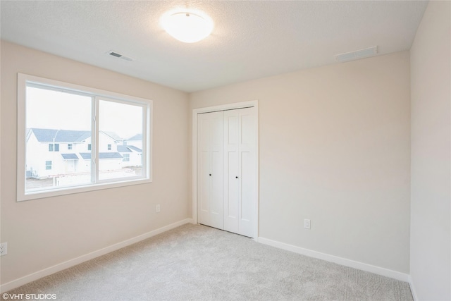 unfurnished bedroom featuring baseboards, visible vents, light carpet, and a closet