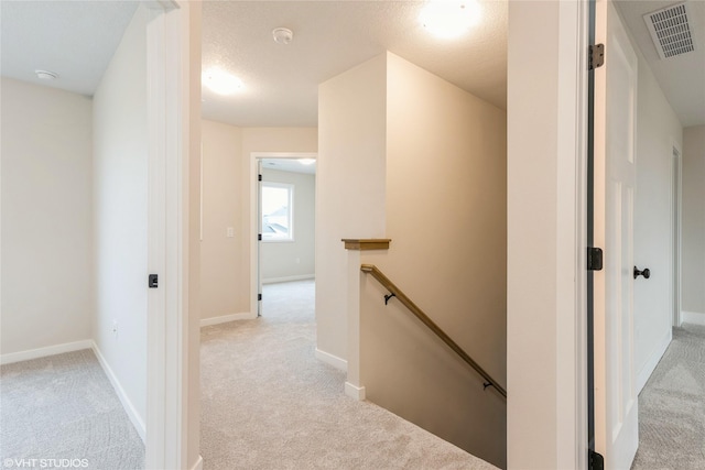 corridor featuring light colored carpet, an upstairs landing, and visible vents