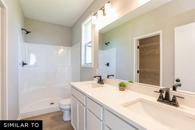 bathroom with hardwood / wood-style flooring, toilet, vanity, and walk in shower