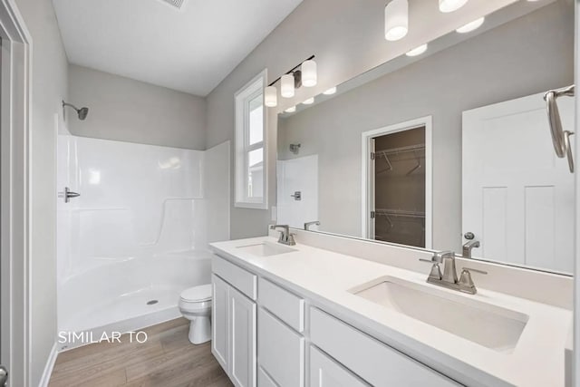 bathroom featuring hardwood / wood-style flooring, vanity, toilet, and walk in shower