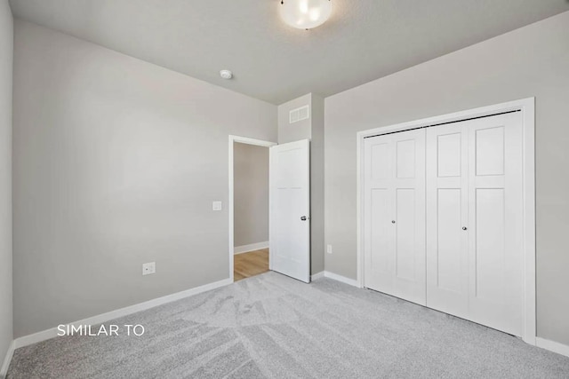 unfurnished bedroom with a closet and light carpet