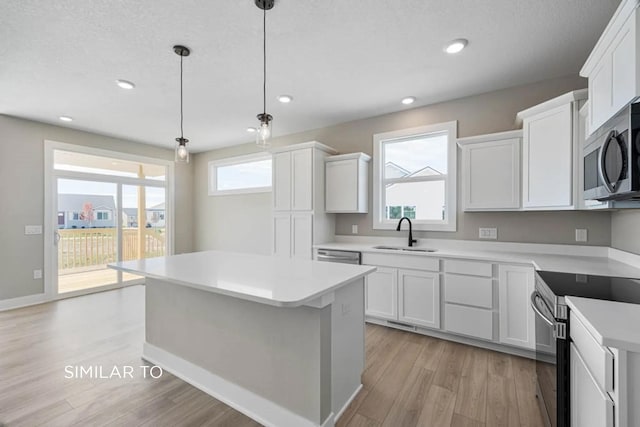 kitchen featuring sink, hanging light fixtures, a kitchen island, stainless steel appliances, and white cabinets