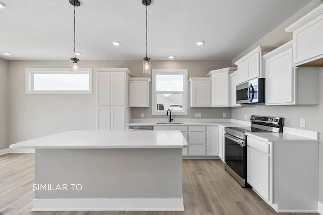 kitchen with white cabinetry, appliances with stainless steel finishes, a center island, and pendant lighting