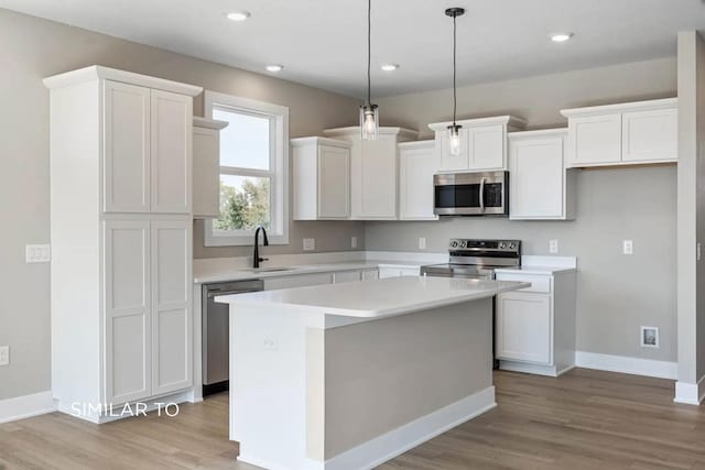 kitchen with white cabinetry, sink, stainless steel appliances, and a center island