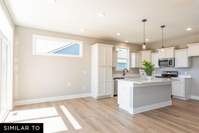 kitchen with pendant lighting, white cabinetry, stainless steel appliances, and a kitchen island