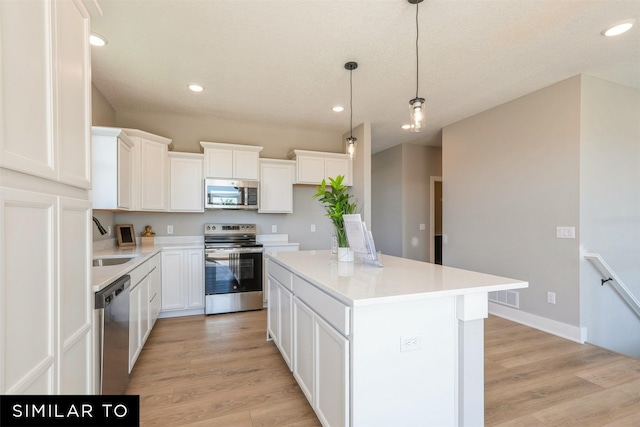 kitchen with a kitchen island, appliances with stainless steel finishes, white cabinets, and decorative light fixtures