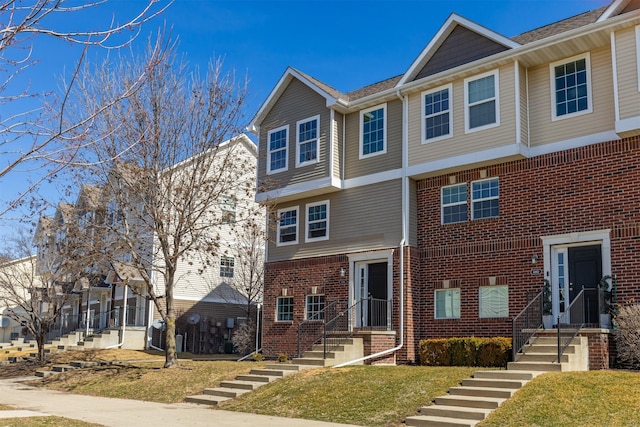 multi unit property with a front lawn and brick siding