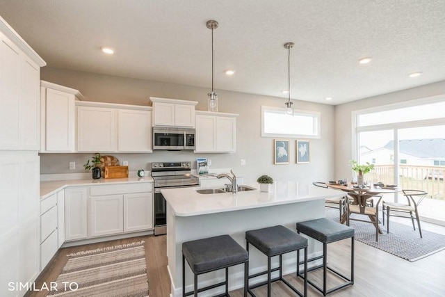 kitchen with stainless steel appliances, sink, hanging light fixtures, and white cabinets