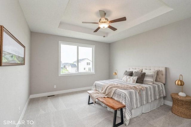 carpeted bedroom featuring a raised ceiling and ceiling fan