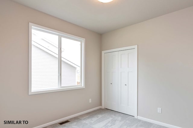 unfurnished bedroom with a closet and light carpet